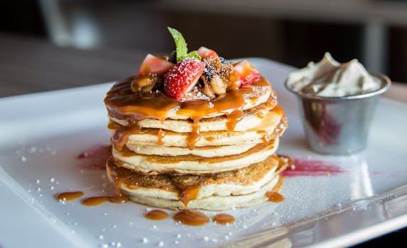 Home Mouthwatering pancakes with strawberries, nuts, and syrup on a plate.